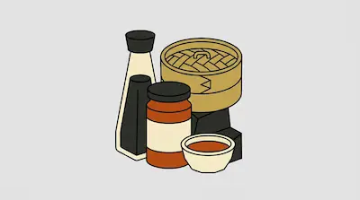 A bottle of soy sauce, a jar of chili oil, a bamboo steamer, and a small bowl of dipping sauce.