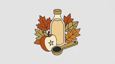 A bottle of liquid, a sliced apple, and a wooden spoon filled with dark liquid are surrounded by autumn leaves.