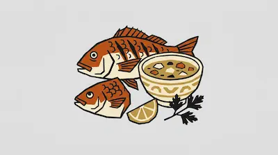Two orange and white fish next to a bowl of soup, a lemon wedge, and a sprig of parsley.