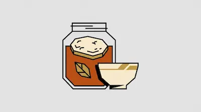 A jar filled with brown liquid and a leaf has a thick disc floating on top, with a small bowl sitting next to it.
