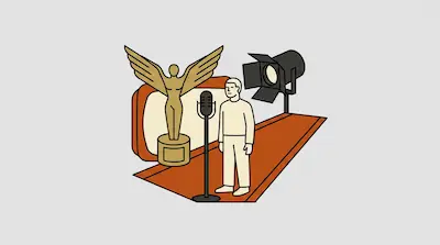 A person stands on a red carpet behind a microphone, with a large winged trophy and a studio spotlight in the background.